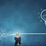 Una persona in piedi davanti a una parete blu, con un tratto grafico che parte da una linea aggrovigliata e si distende fino a formare una lampadina luminosa stilizzata, a rappresentare il passaggio dal disordine alla chiarezza concettuale, tipico della definizione delle regole del lavoro agile.