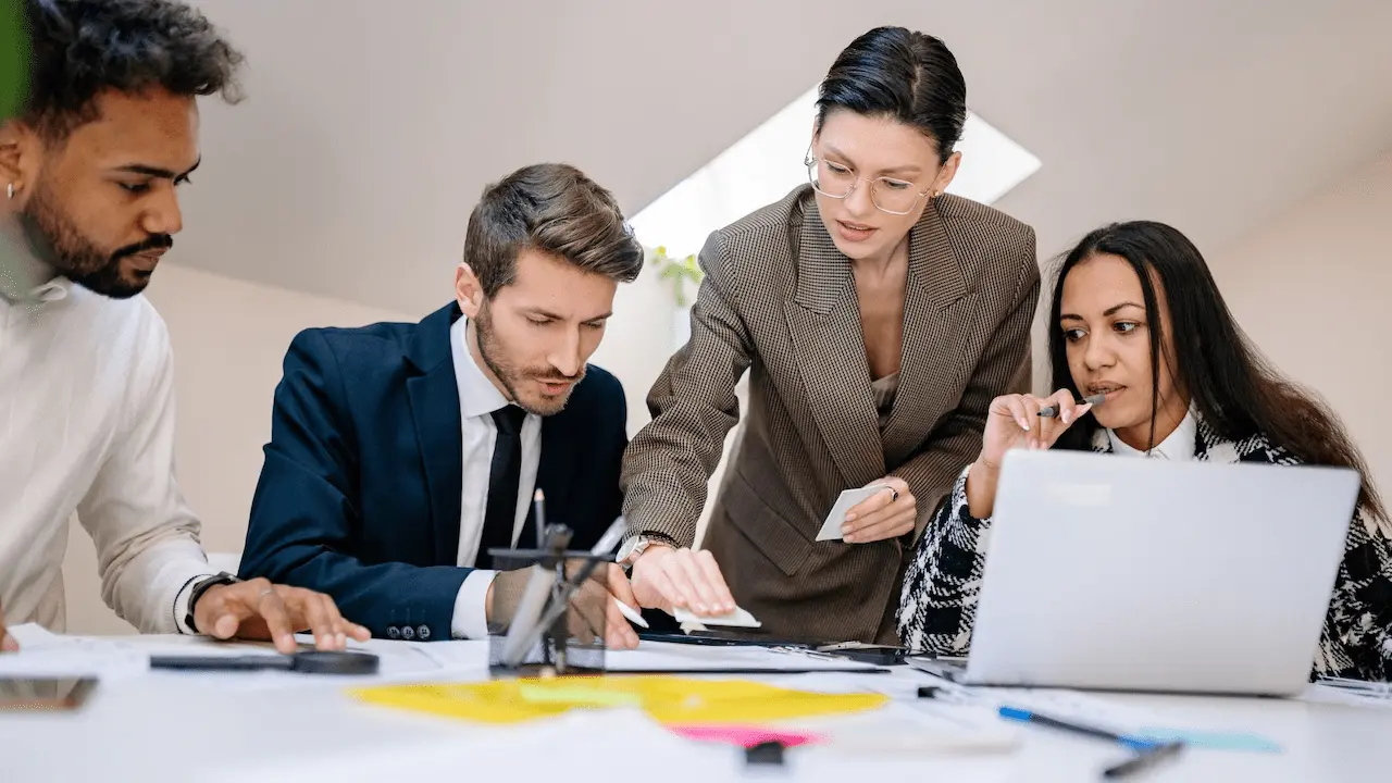 Persone sedute attorno a un tavolo in un ambiente d’ufficio mentre analizzano documenti e dati, con laptop, fogli, post‑it e strumenti di lavoro, a rappresentare attività di consulenza e verifica contributiva aziendale.