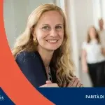 Persona seduta a un tavolo in un ambiente d’ufficio, con una grande grafica arancione curva sul lato sinistro e una fascia blu inferiore con testo dedicato alla parità di genere, a rappresentare contenuti informativi sul tema del Gender Equality.