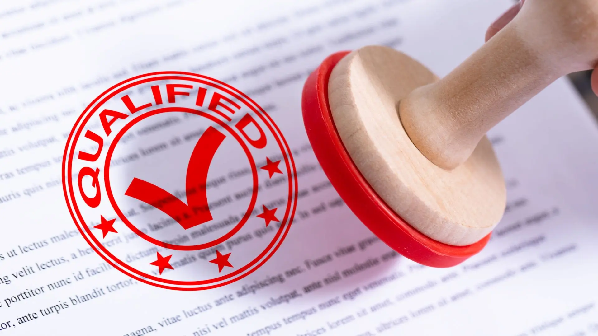 Timbro con la scritta “QUALIFIED” impresso su un documento, a rappresentare il concetto di certificazione, idoneità e conformità a standard ufficiali.
