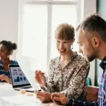 Persone sedute attorno a un tavolo in un ufficio mentre analizzano documenti e dati, con un computer portatile che mostra grafici sullo schermo, a rappresentare la valutazione degli incentivi occupazionali destinati a giovani e donne nella Regione Lazio.