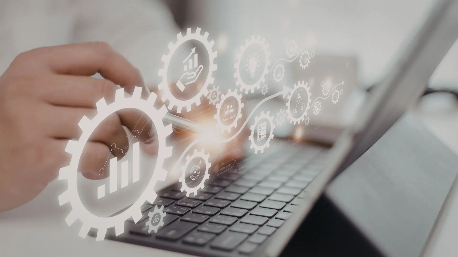 Mano posizionata sopra la tastiera di un computer portatile, con icone digitali sovrapposte che raffigurano ingranaggi, grafici e simboli di processo, a rappresentare l’automazione e il controllo dei flussi nel payroll e nella gestione HR.