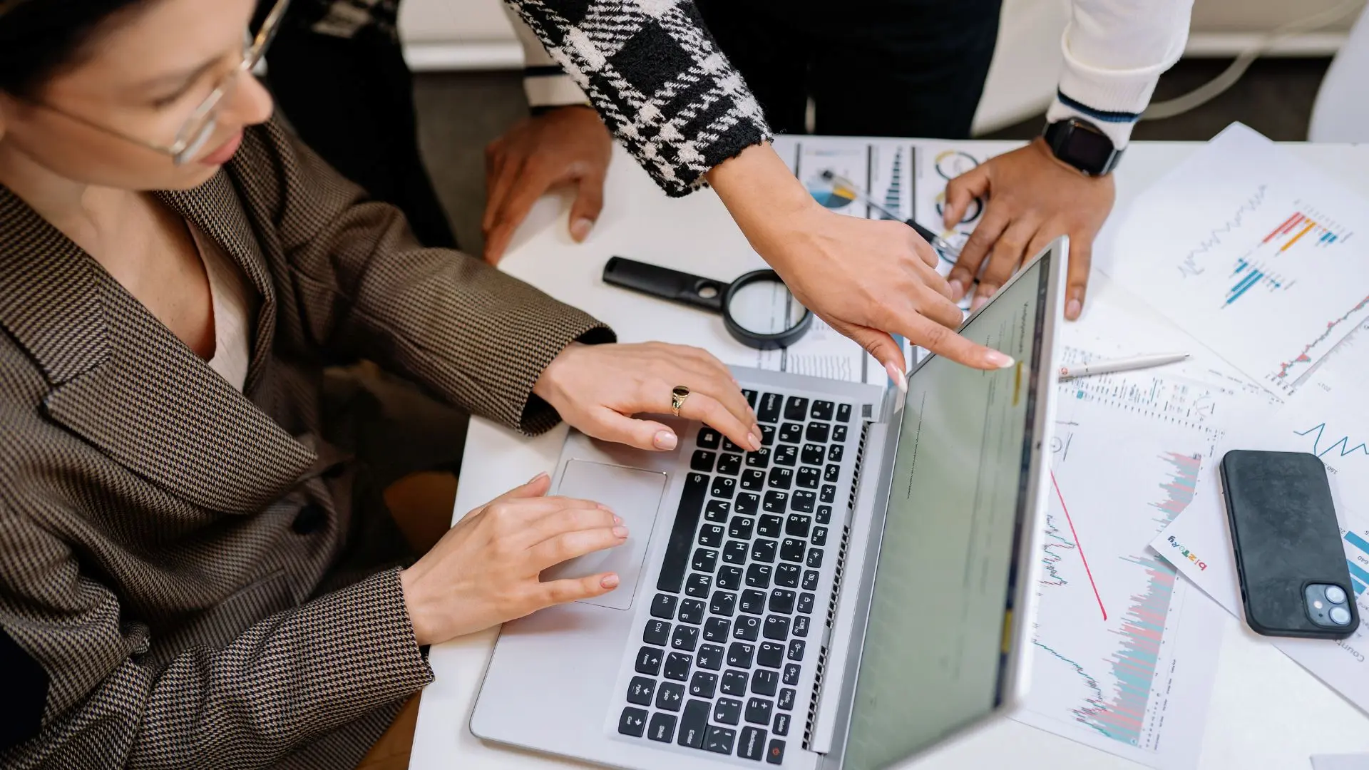 Persone riunite attorno a un computer portatile in un ufficio, mentre analizzano documenti e grafici, a rappresentare la gestione amministrativa delle assunzioni agevolate e la verifica dei requisiti per l’esonero contributivo