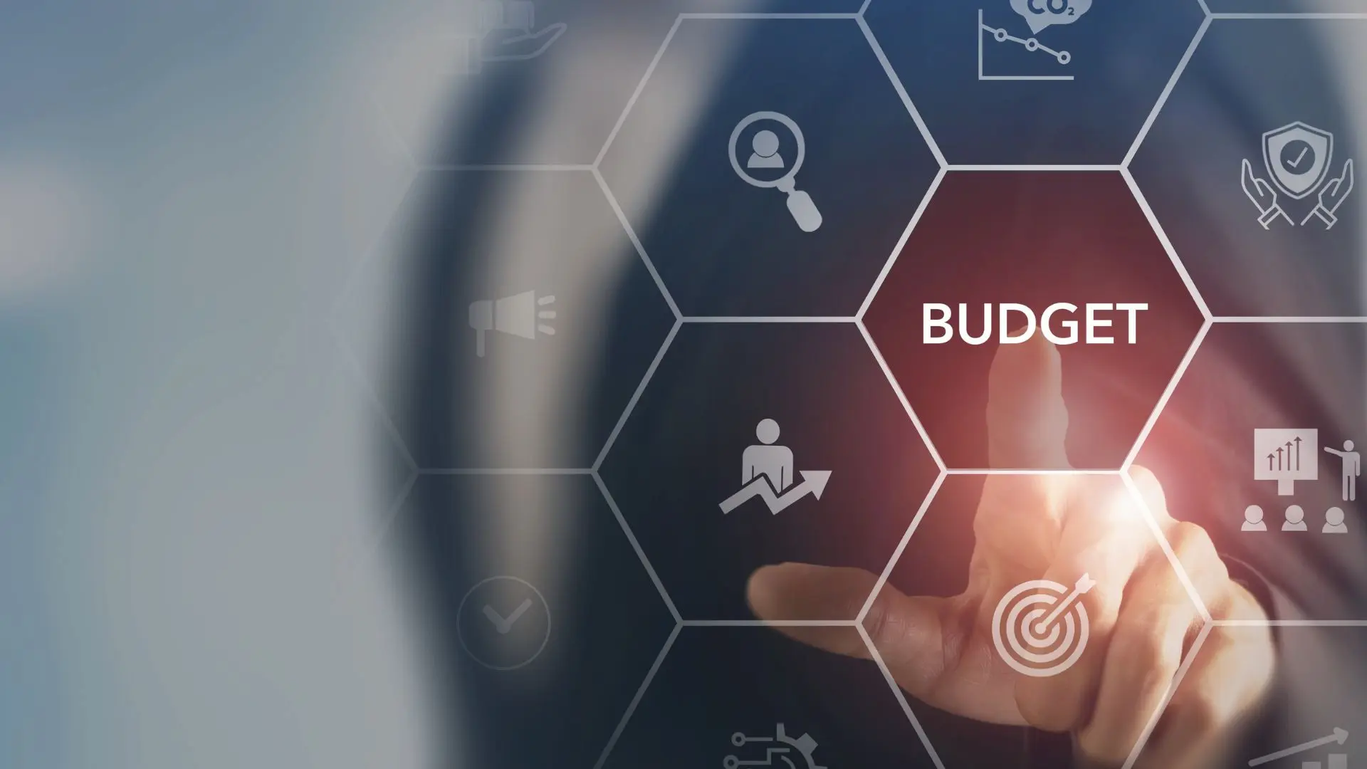 Interfaccia digitale composta da esagoni che contengono icone relative a lavoro, gestione aziendale e finanza, mentre una mano seleziona un riquadro con la scritta “BUDGET”, a rappresentare pianificazione economica e misure previste dalla Legge di Bilancio