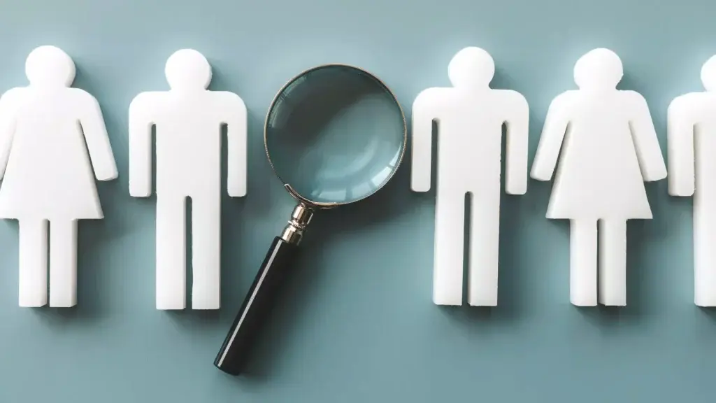 Sagome stilizzate di persone allineate e una lente d’ingrandimento posizionata sopra una delle figure, a rappresentare processi di selezione del personale e valutazione dei candidati.