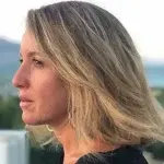 Figura di profilo con capelli chiari e taglio medio, in un ambiente esterno con paesaggio sfocato sullo sfondo, a rappresentare un’intervista sul tema della leadership e della sostenibilità aziendale.