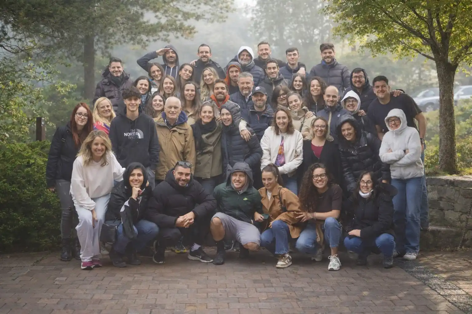 Foto di gruppo del team di Fiabilis Consulting Group scattata all'aperto in un'area alberata durante un momento di condivisione e team building. I numerosi colleghi e colleghe, in abbigliamento informale, sorridono compatti guardando l'obiettivo. L'immagine rappresenta l'affiatamento, l'inclusività e l'importanza del fattore umano, elementi fondanti della cultura aziendale.