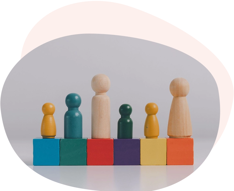 Sei pedine di legno di diverse dimensioni e colori allineate su cubi colorati, a simboleggiare la valorizzazione della diversità e l'inclusione aziendale tramite l'Inclusion Management Program.