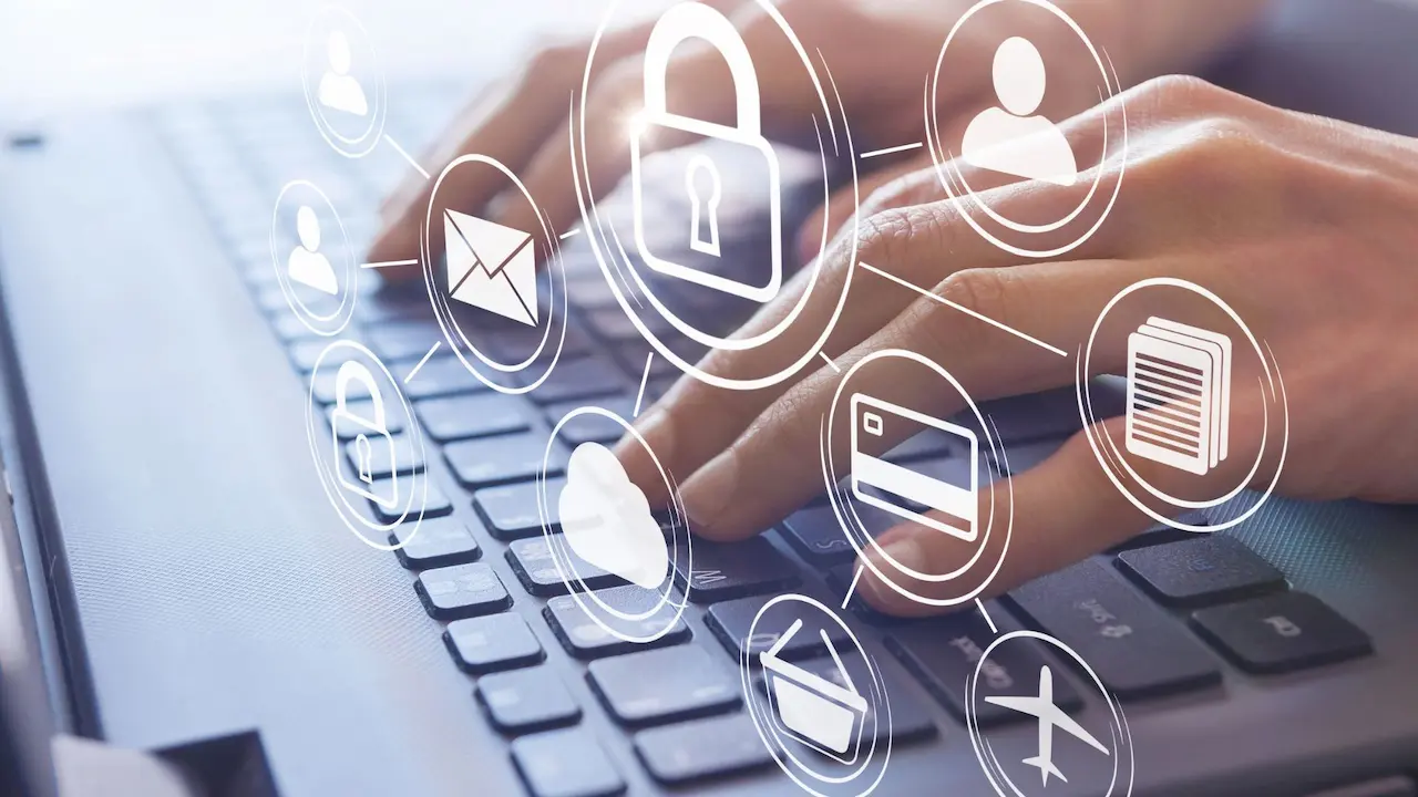 Mani che digitano su una tastiera con icone simboliche di sicurezza informatica, protezione dati e digitalizzazione dei processi aziendali