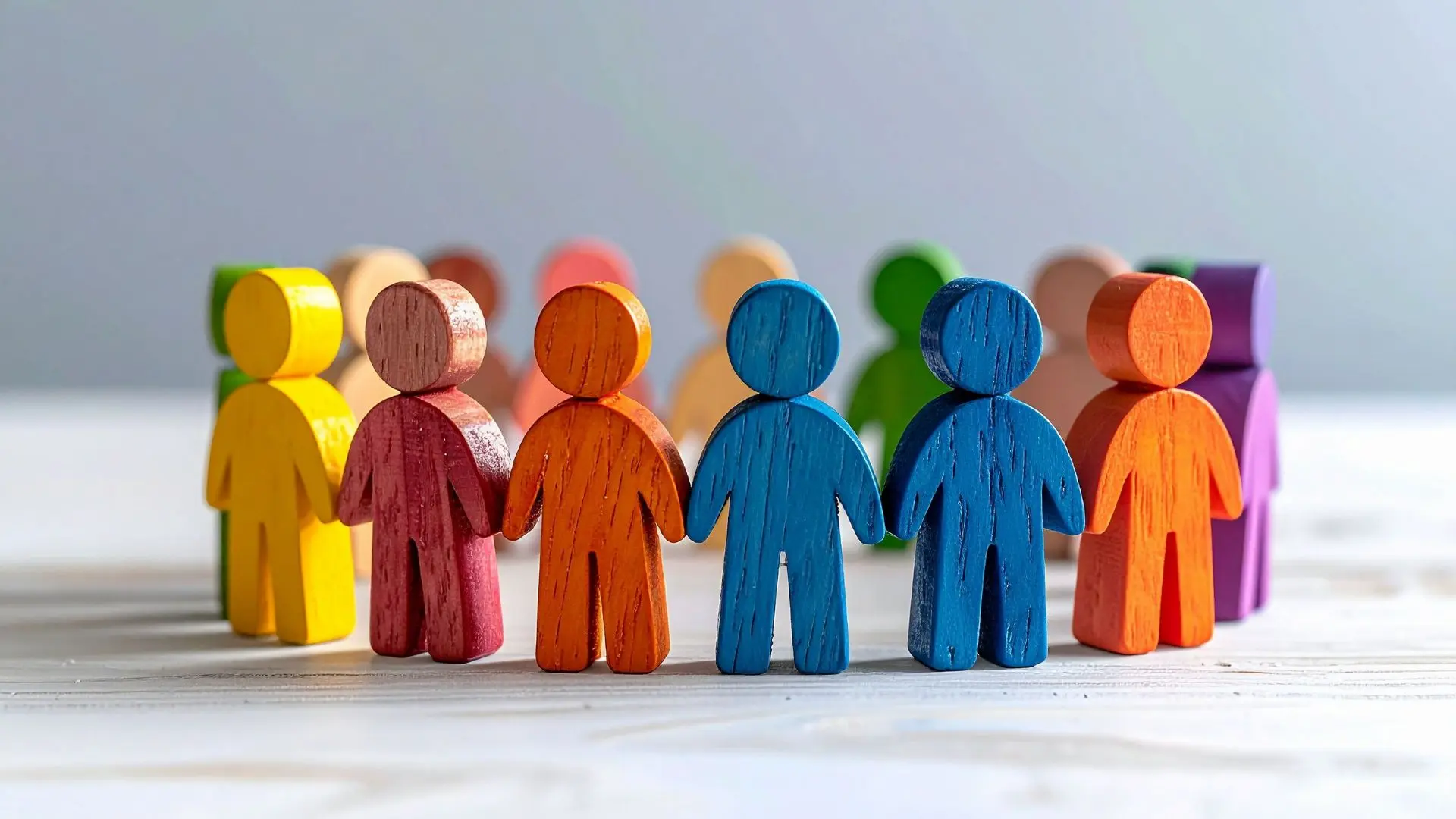Figure stilizzate in legno di colori diversi disposte in cerchio su un piano chiaro, metafora dell'inclusione lavorativa e della valorizzazione delle diversità in azienda secondo la Legge 68/99