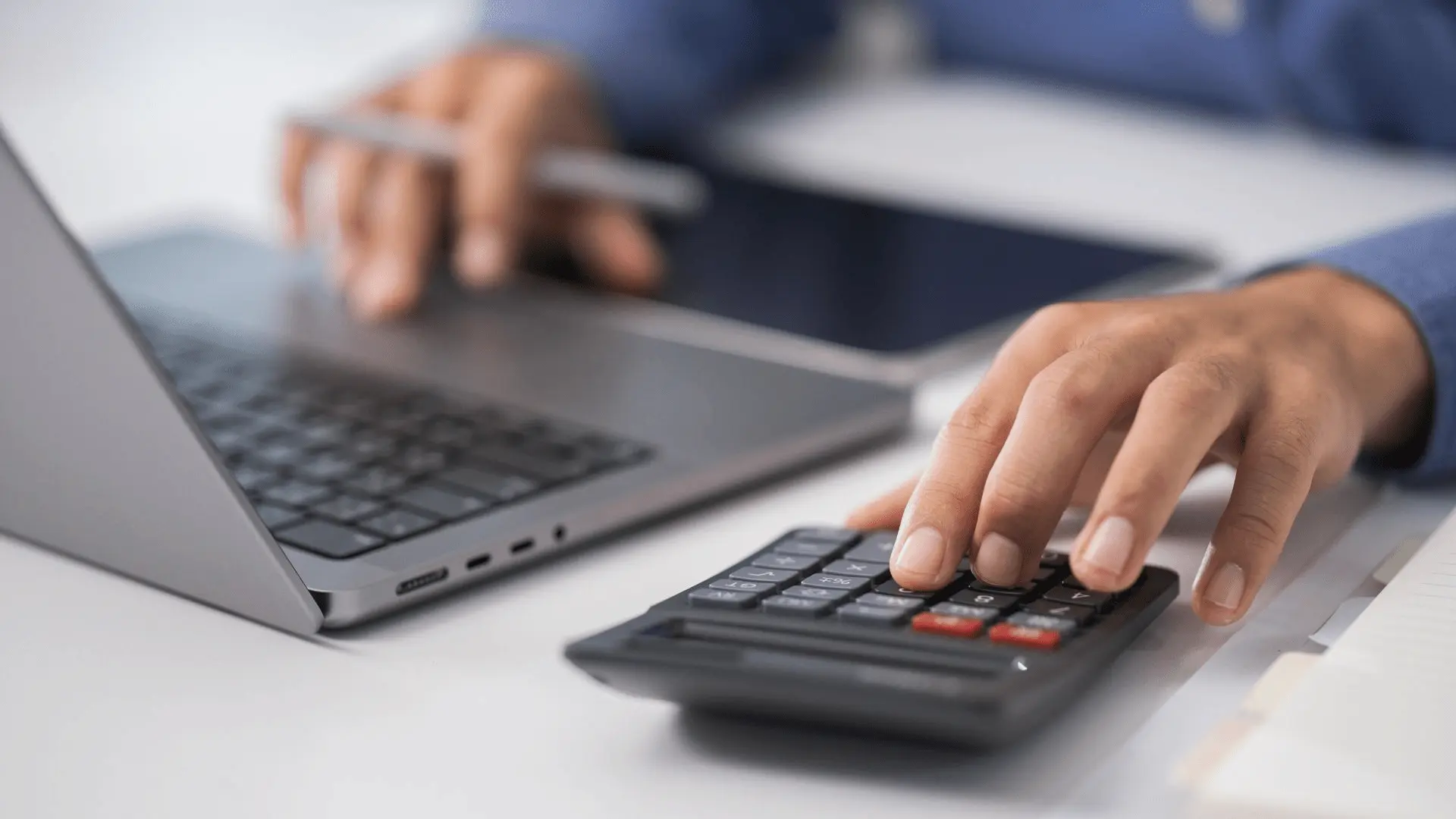 Consulente aziendale calcola con calcolatrice e laptop gli importi del recupero contributivo INPS per l'ottimizzazione del costo del lavoro