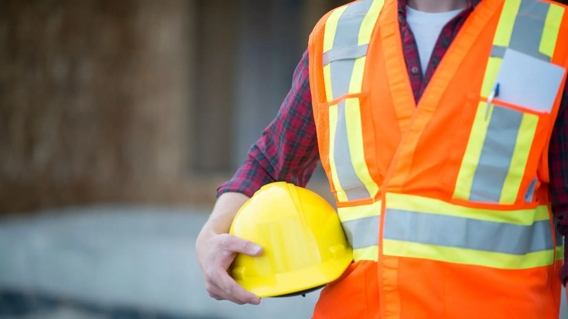Lavoratore con gilet ad alta visibilità ed elmetto di protezione in mano, a rappresentare i DPI e il sistema di prevenzione previsto dal D.Lgs. 81/2008