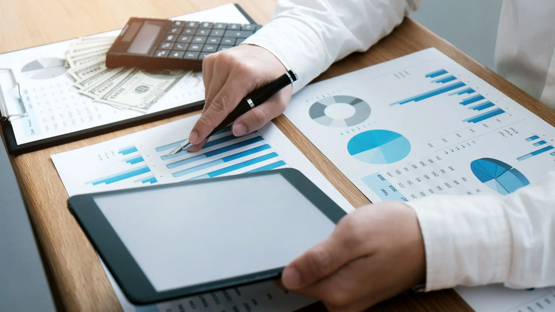 Professionista analizza con penna e calcolatrice report con grafici sui costi aziendali
