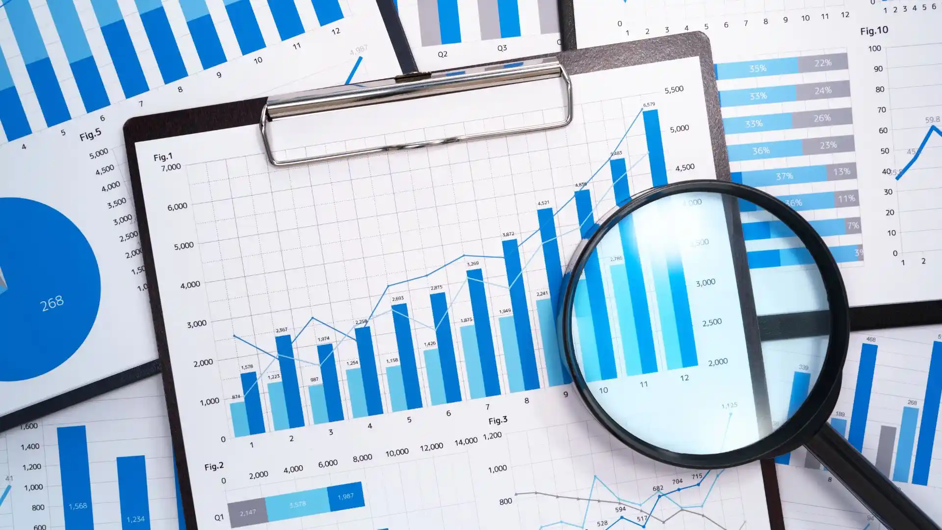 Lente d'ingrandimento appoggiata su grafici e tabelle stampate in fase di analisi